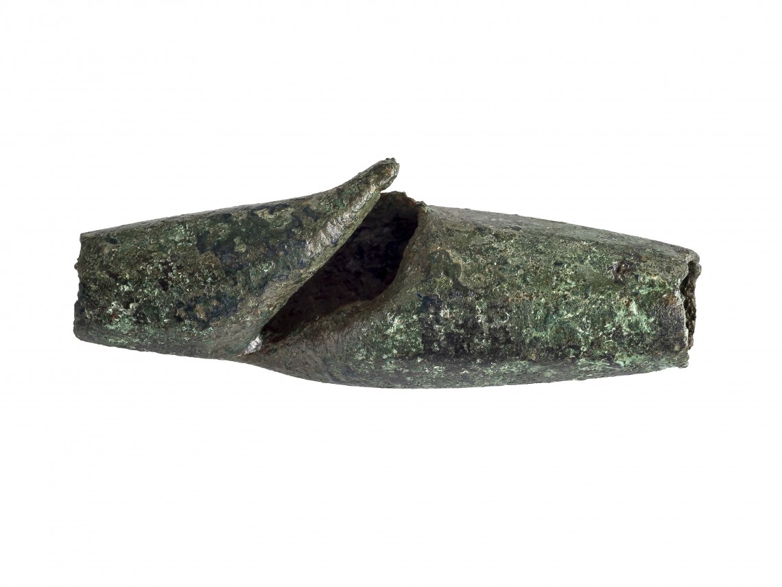Bronzene Riemenhülse vom Pferdegeschirr mit den Spuren eines Schwerthiebs